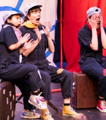 Three people dressed in black and wearing hats looking frightened by something