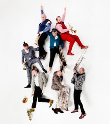 Seven men with brass instruments appearing as if they are falling 